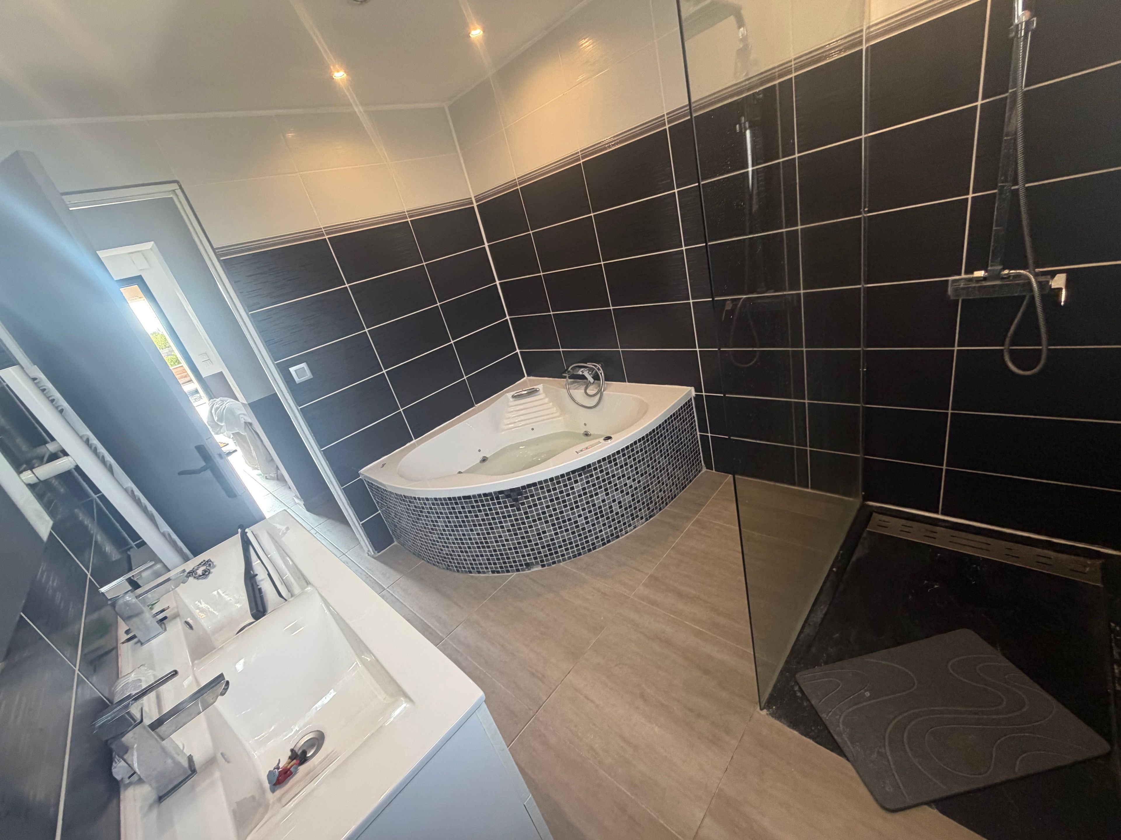 A modern bathroom with a freestanding bathtub, a glass-enclosed shower, and a vanity with a sink and mirror.