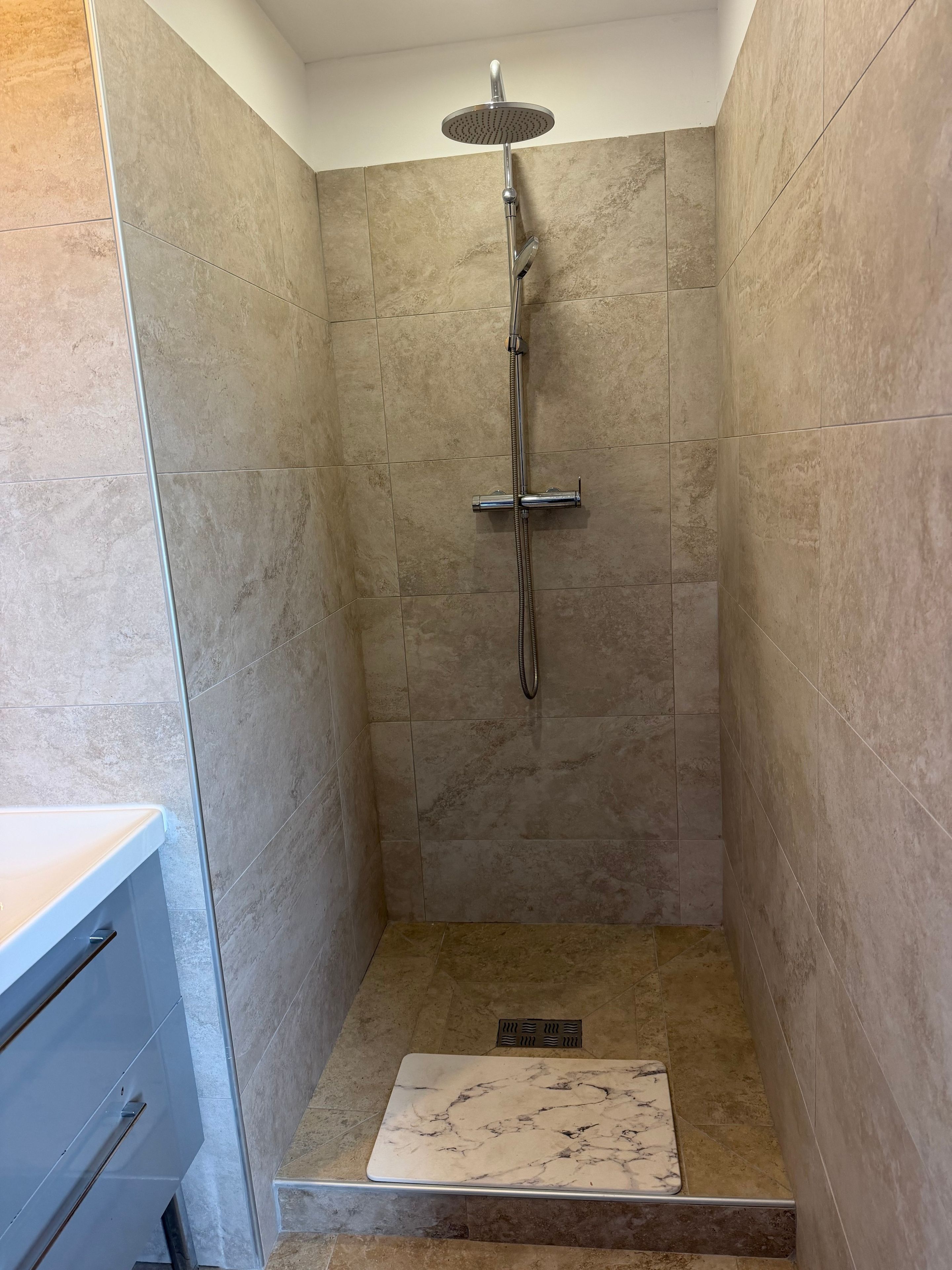 Eine Dusche mit Handbrause und Wandarmatur.