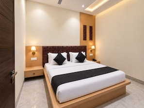 A modern hotel room with a large bed, wooden headboard, bedside lamps, and a marble floor. - Classic Hotel Shiva Residency (Amritsar)