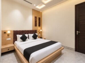 A hotel room with a bed, bedside tables, a nightstand, and a door. - Classic Hotel Shiva Residency (Amritsar)