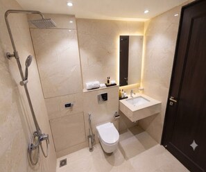 A modern bathroom with a shower, toilet, sink, and a dark wooden door. - Deluxe Room Jessore Road Kolkata Airport (Barakpur)