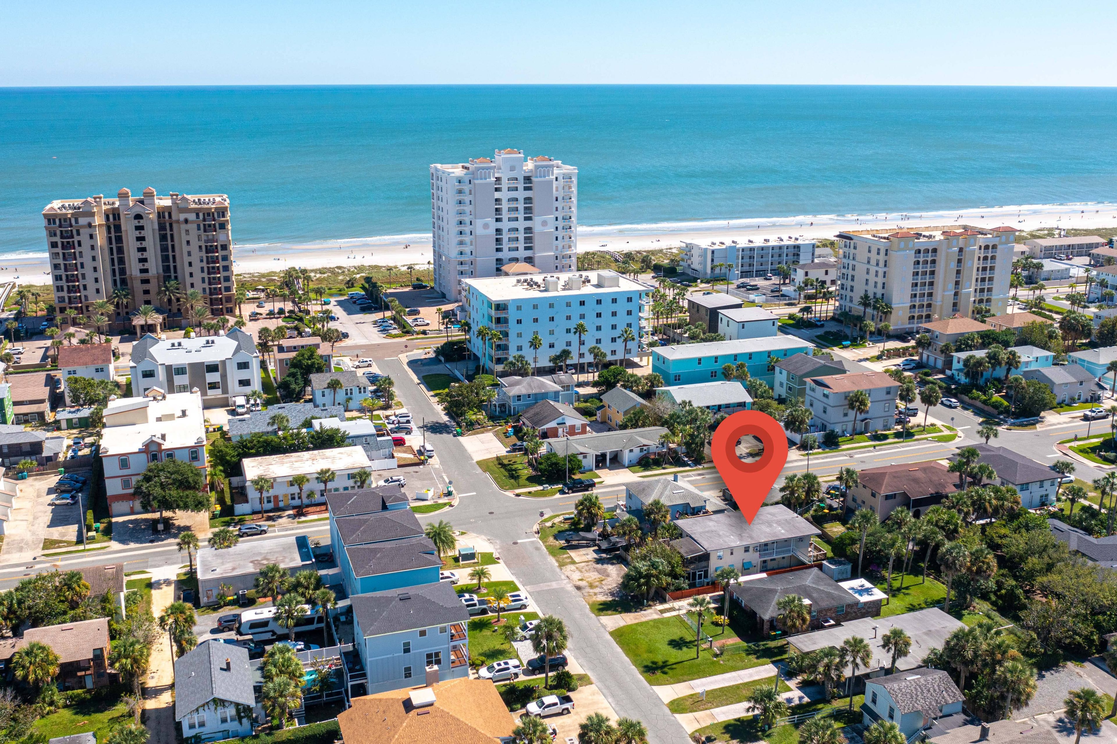 A coastal residential area with beachfront properties, a central road, and a red location marker.