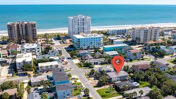 A coastal residential area with beachfront properties, a central road, and a red location marker.