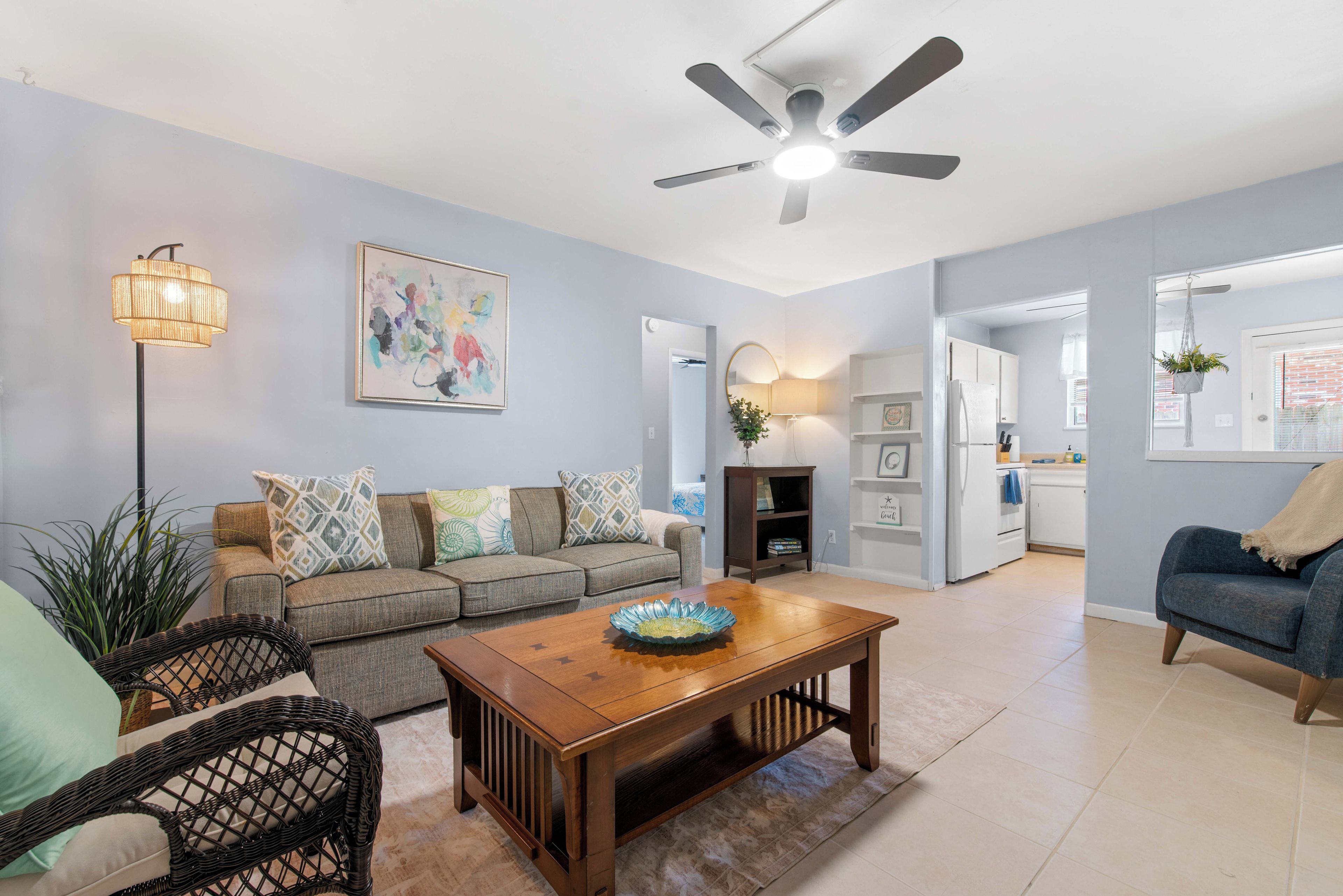 A living room with a sofa, a coffee table, a floor lamp, and a ceiling fan.