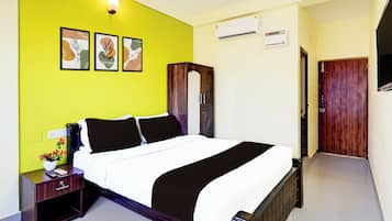 Een slaapkamer met een bed, nachtkastje, kledingkast en een wandairconditioner, plus een deur.