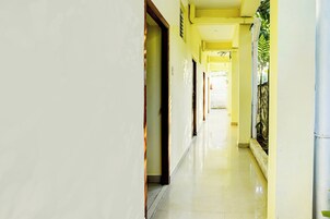 Un pasillo con puertas a un lado y una pared con ventana al otro.