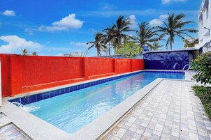 Piscina com parede vermelha e deck revestido em azulejos azuis.
