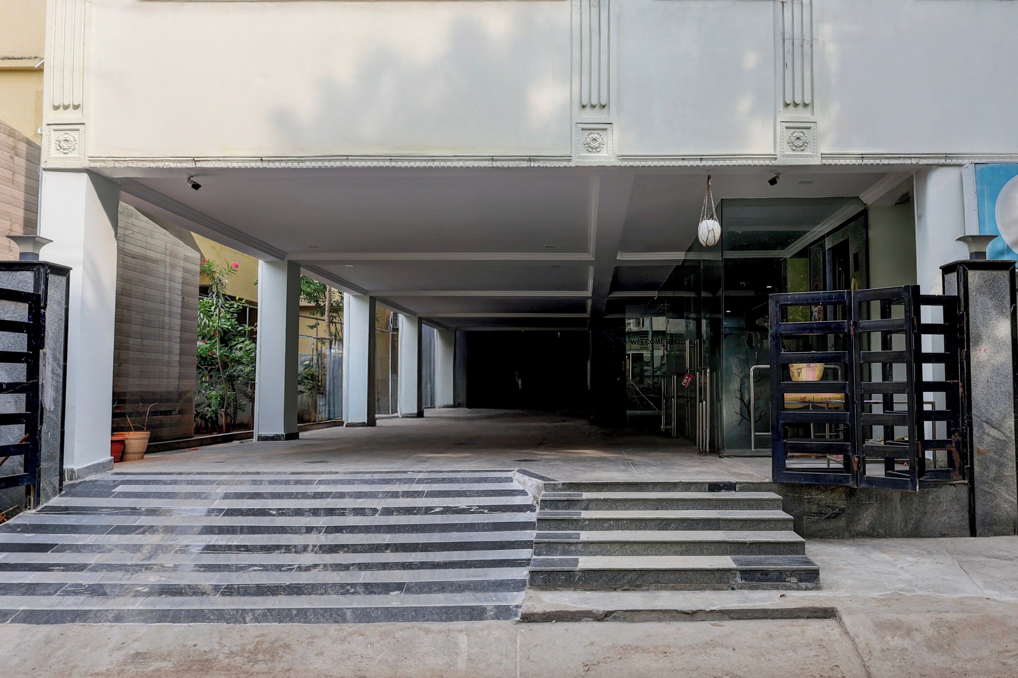 A building entrance with a covered walkway, steps leading to a door, and a security gate.