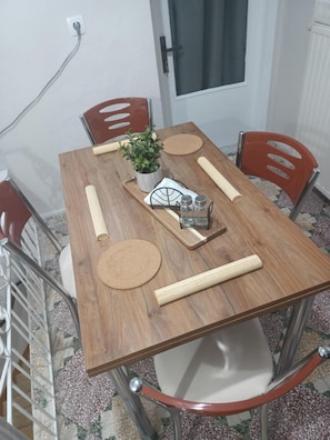 A dining table with four chairs, a potted plant, a metal tray, and salt and pepper shakers. - Stone House 'Medieval-Style 1905 Stone House' (Πυργί)