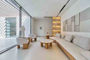 A modern living room with a sofa, chairs, a coffee table, and a large window. - Sleek 4BR Villa Private Pool Beach Al Zorah (Ajman)