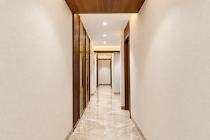 A corridor with a wooden ceiling, white walls, and a marble floor. - Townhouse Oak DLF Newtown Bus Terminal (Barasat)