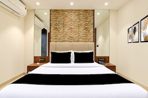 A hotel room with a bed, bedside tables, a mirror, and a wall with a textured pattern. - Townhouse Oak DLF Newtown Bus Terminal (Barasat)
