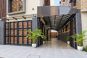A covered walkway with a modern design, flanked by a wooden fence and potted plants. - Townhouse Oak DLF Newtown Bus Terminal (Barasat)