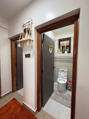 A modern bathroom with a toilet, a towel rack, and a mirror. - Nakuru View Palace Apartment (Nakuru)