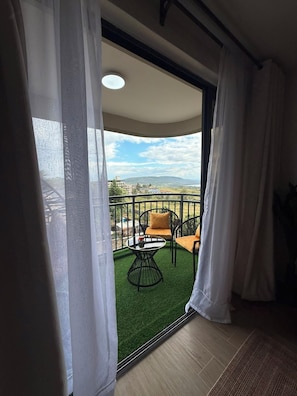A balcony with a view of a green landscape and distant buildings. - Nakuru View Palace Apartment (Nakuru)