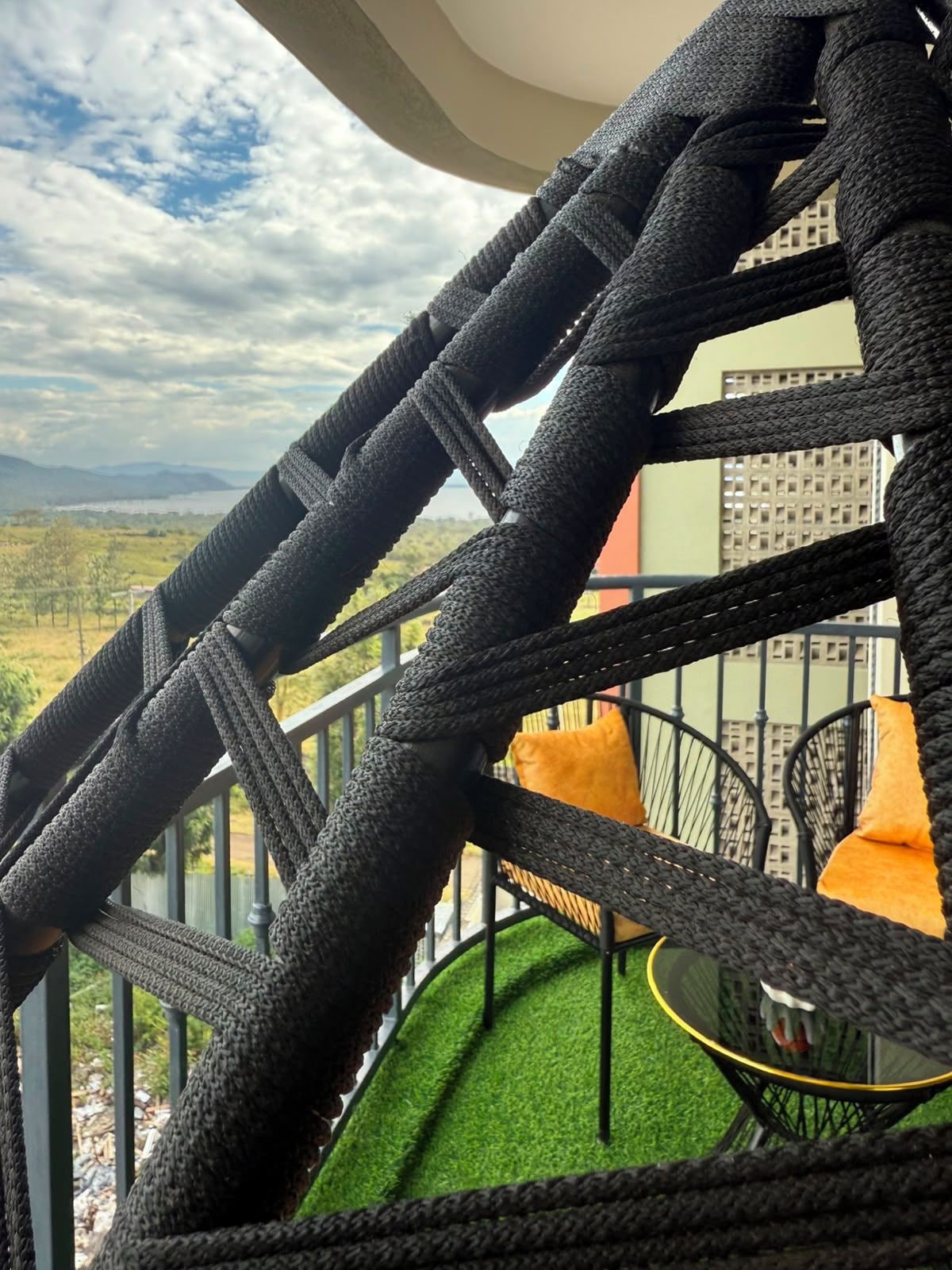 A balcony with a view of a green landscape and distant mountains.