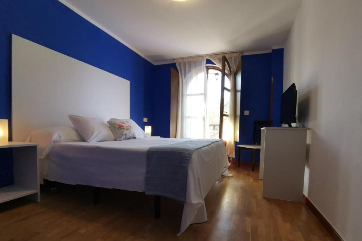 A bedroom with a bed, bedside table, and a television.