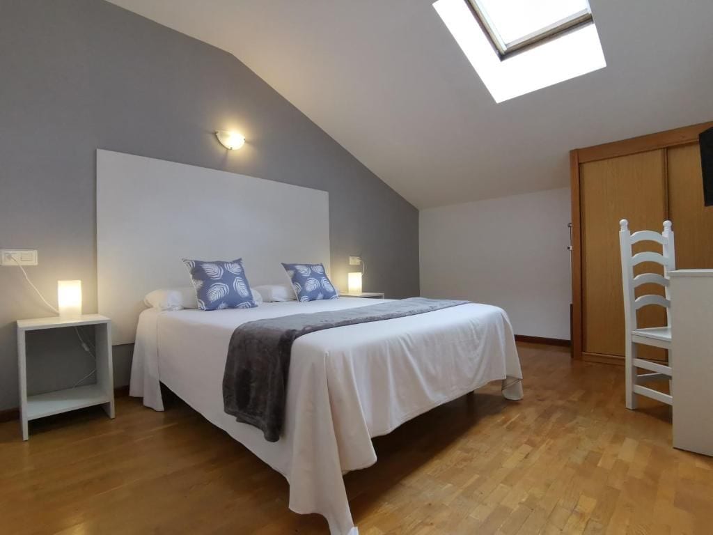 Un dormitorio con cama, mesitas de noche, armario y tragaluz.
