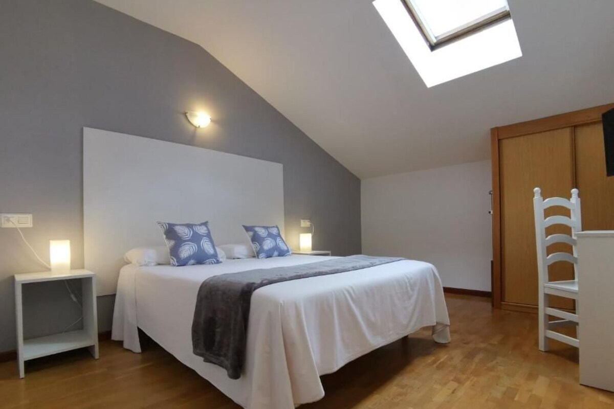A bedroom with a bed, bedside tables, a wardrobe, and a skylight.