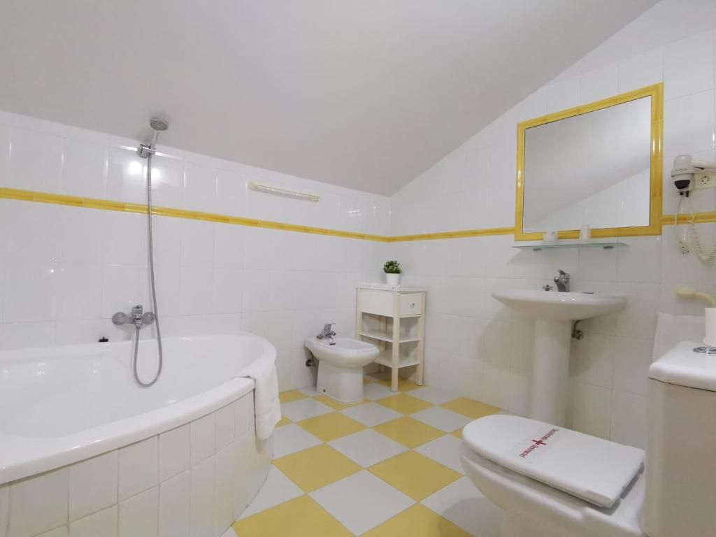 Een badkamer met een bad, toilet, bidet en een wastafel.