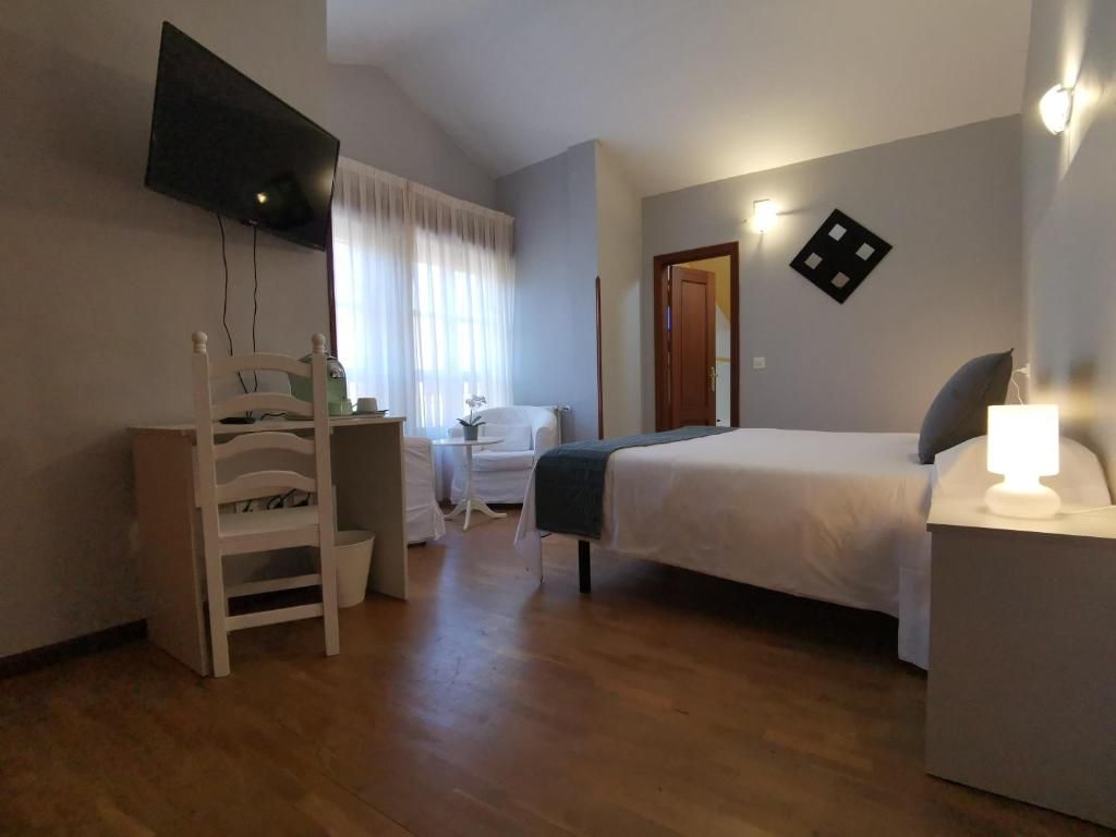 Een slaapkamer met een bed, een bureau, een stoel, een televisie en een bedlamp.