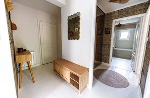A hallway with a wooden bench, a door, a mirror, and a patterned wall. - New Listing (Anglet)