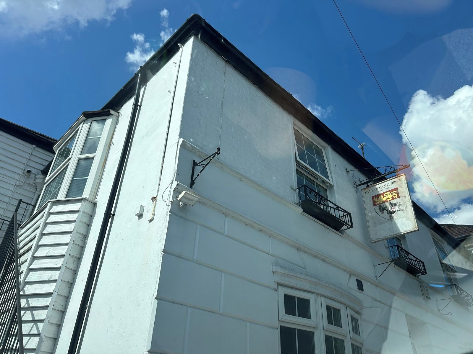 A building with a white facade, a visible balcony, and a sign indicating a historical building.
