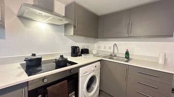 A compact kitchen with a built-in oven, a washing machine, and a coffee maker.