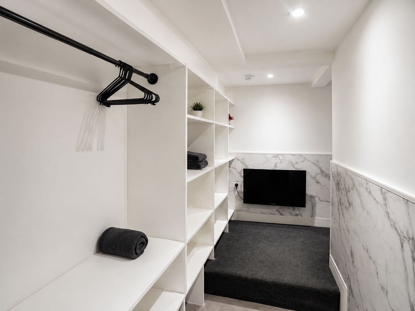 A modern bathroom with a built-in TV, marble backsplash, and a towel rack.