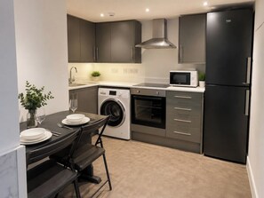 Cocina compacta con lavadora, horno, microondas y un refrigerador negro.