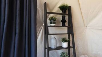 Une étagère en bois foncé, en forme d’échelle, avec des plantes en pot, placée devant un mur de couleur beige.