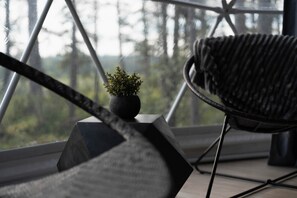 A modern interior with a geometric floor plan, a black woven chair, and a small potted plant on a black pedestal.