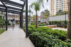 Un espacio al aire libre cubierto con entrada protegida, un camino empedrado y un jardín bien cuidado con diversas plantas.