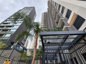 A modern high-rise building with multiple balconies and a gated entrance. - Studio in Vila Olímpia with Pool and Gym (São Paulo)