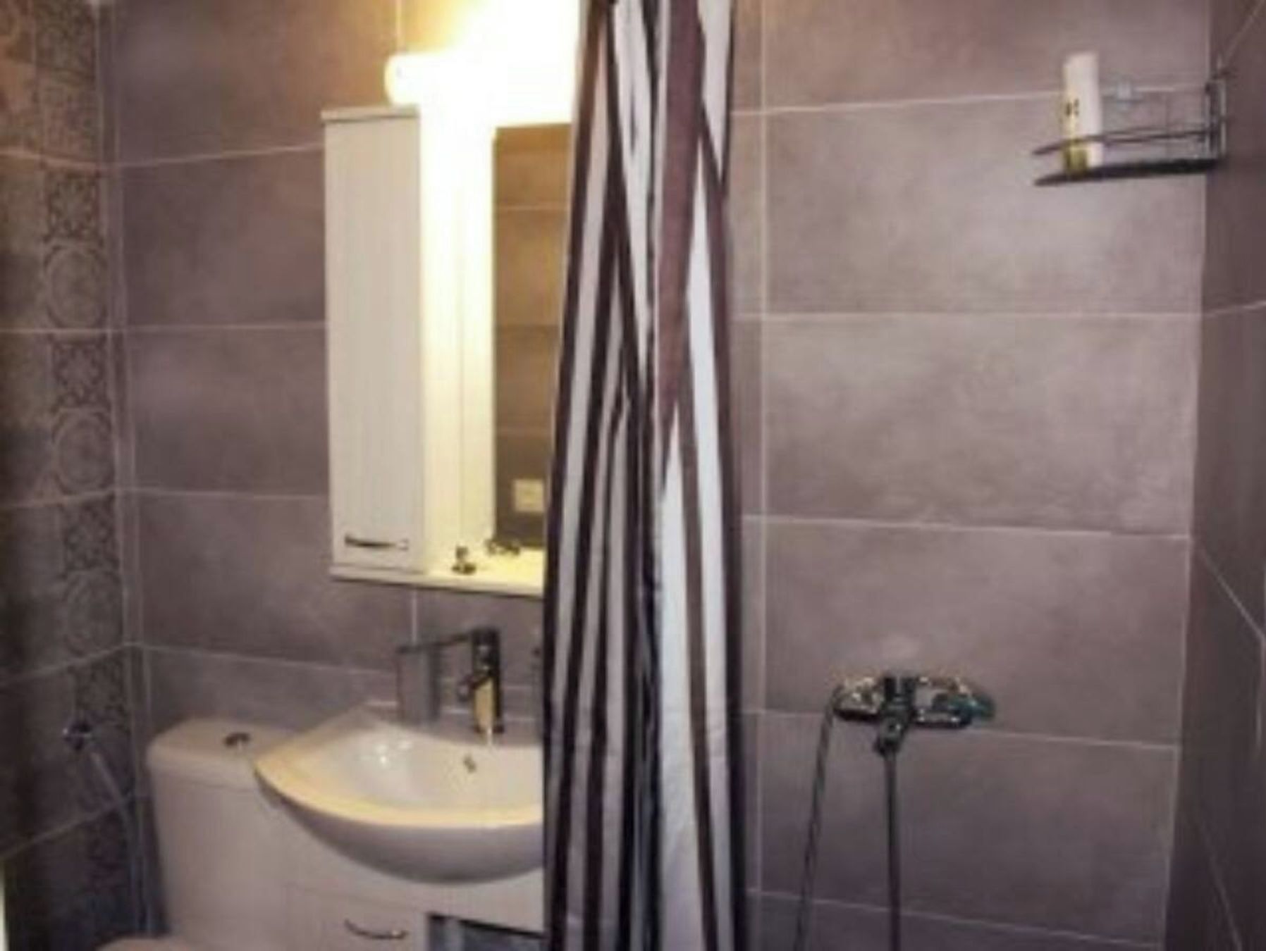 Un baño con lavamanos, espejo y cortina de ducha.