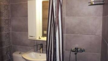 A bathroom with a sink, mirror, and shower curtain.