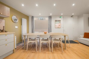 A modern dining area with a wooden table and chairs, a white sofa, and a small painting on the wall. - SmartStay Bird Family Bellecour - Lyon (Lyon)