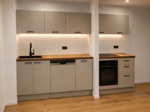 Una cocina moderna con electrodomésticos integrados, encimera de madera y diseño de muebles blancos.