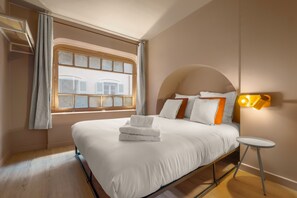 Una habitación de hotel con una cama grande, una mesita pequeña y una ventana con cortinas.