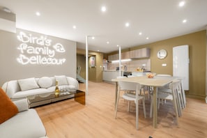Una sala de estar moderna con un sofá, una mesa de centro de vidrio y un comedor con mesa y sillas.