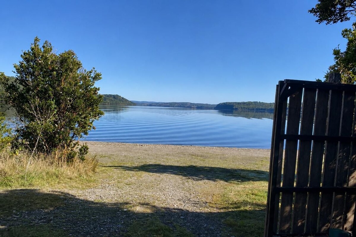 A serene lakeside view with a wooden fence and a grassy area leading to the water.