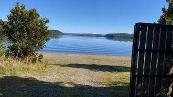 Una vista tranquila del lago con una cerca de madera y un área verde que desciende hacia el agua.