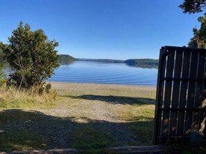 A serene lakeside view with a wooden fence and a grassy area leading to the water. - Mi Refugio del Lago Natri (Chonchi)