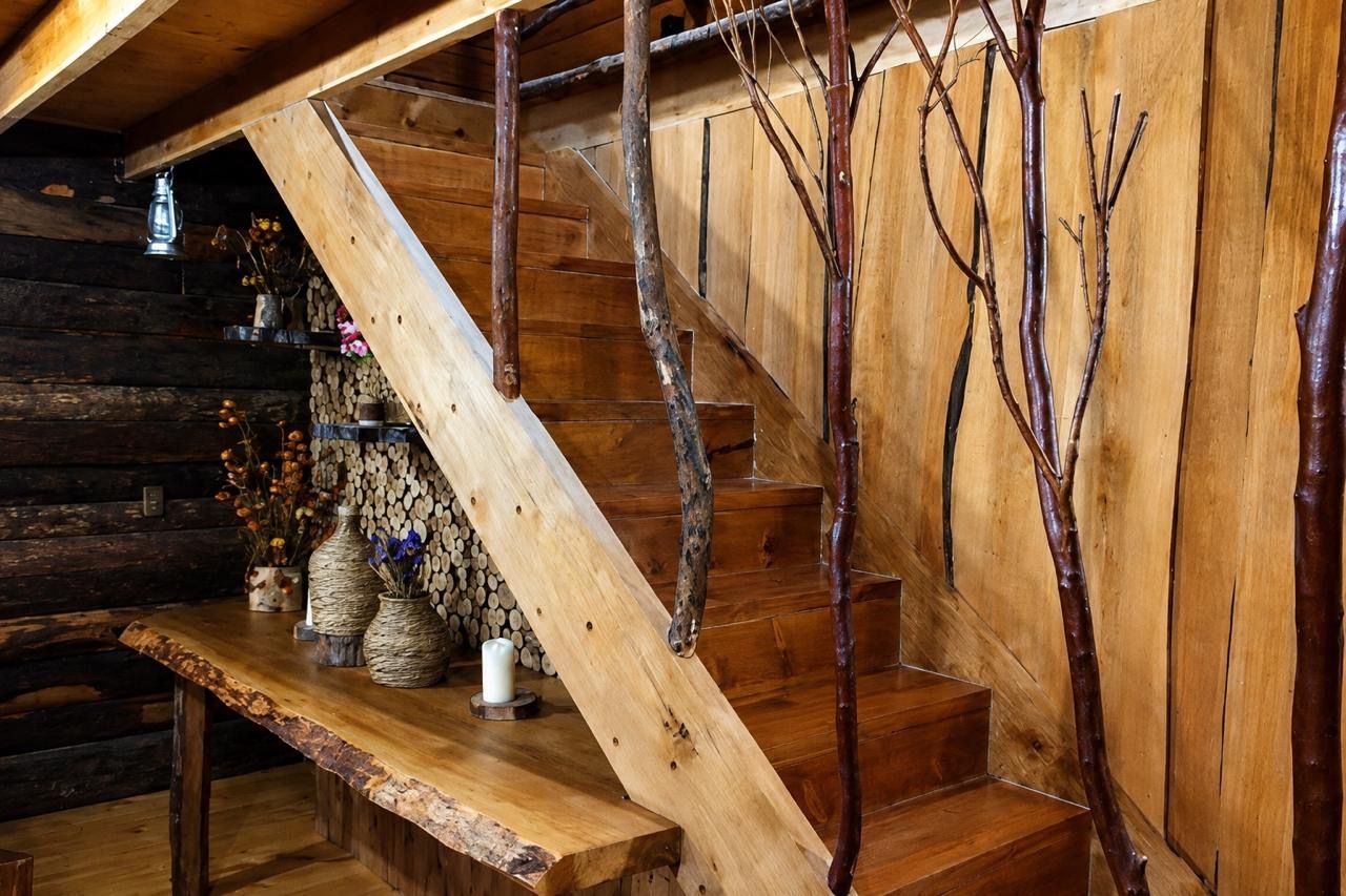 Una escalera de madera con diseño rústico, un banco de madera con adornos y una pared con ramas.