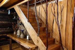A wooden staircase with a rustic design, a wooden bench with decorative items, and a wall with branches. - Mi Refugio del Lago Natri (Chonchi)
