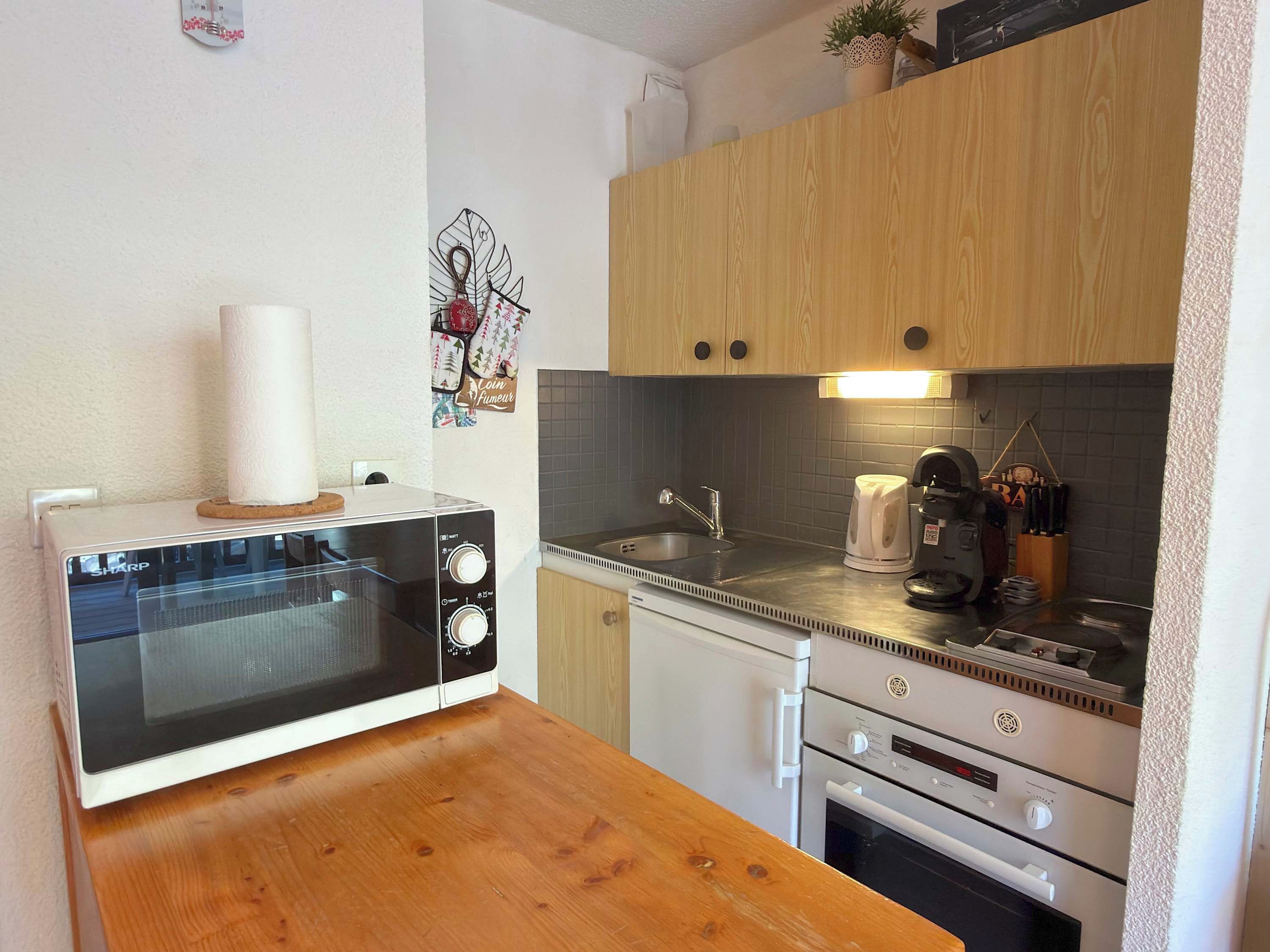 A compact kitchenette with a microwave, a coffee maker, and a sink.