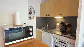 A compact kitchenette with a microwave, a coffee maker, and a sink.
