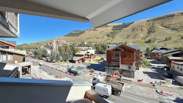Vista di una città con edifici in legno e moderni, un cantiere edile con macchinari pesanti e un cielo azzurro limpido.