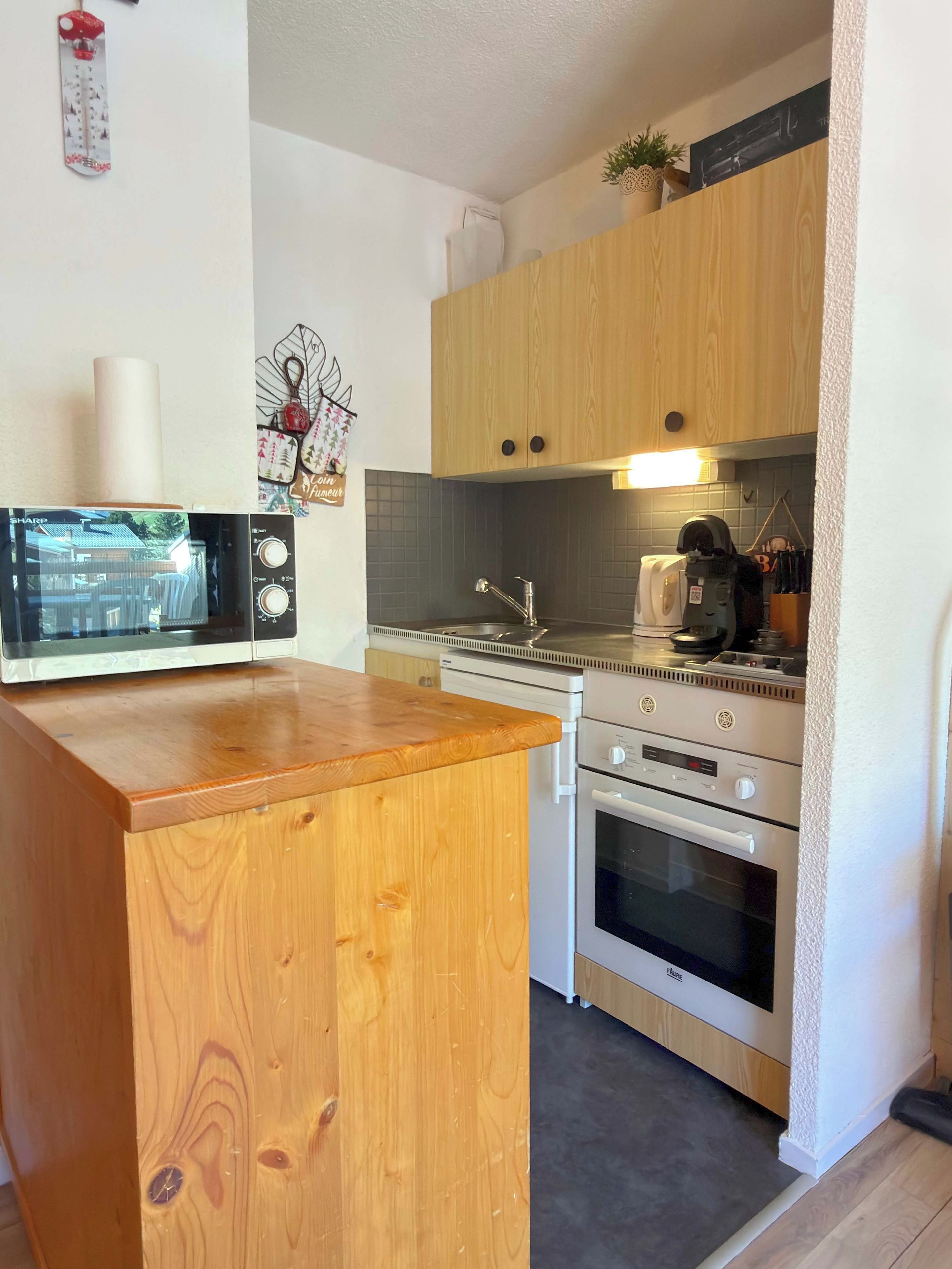 A kitchen with a wooden countertop, a microwave, a stove, and a sink.