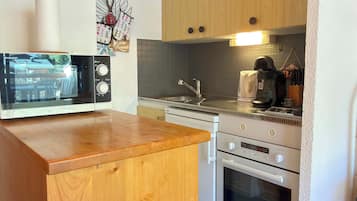 A kitchen with a wooden countertop, a microwave, a stove, and a sink.